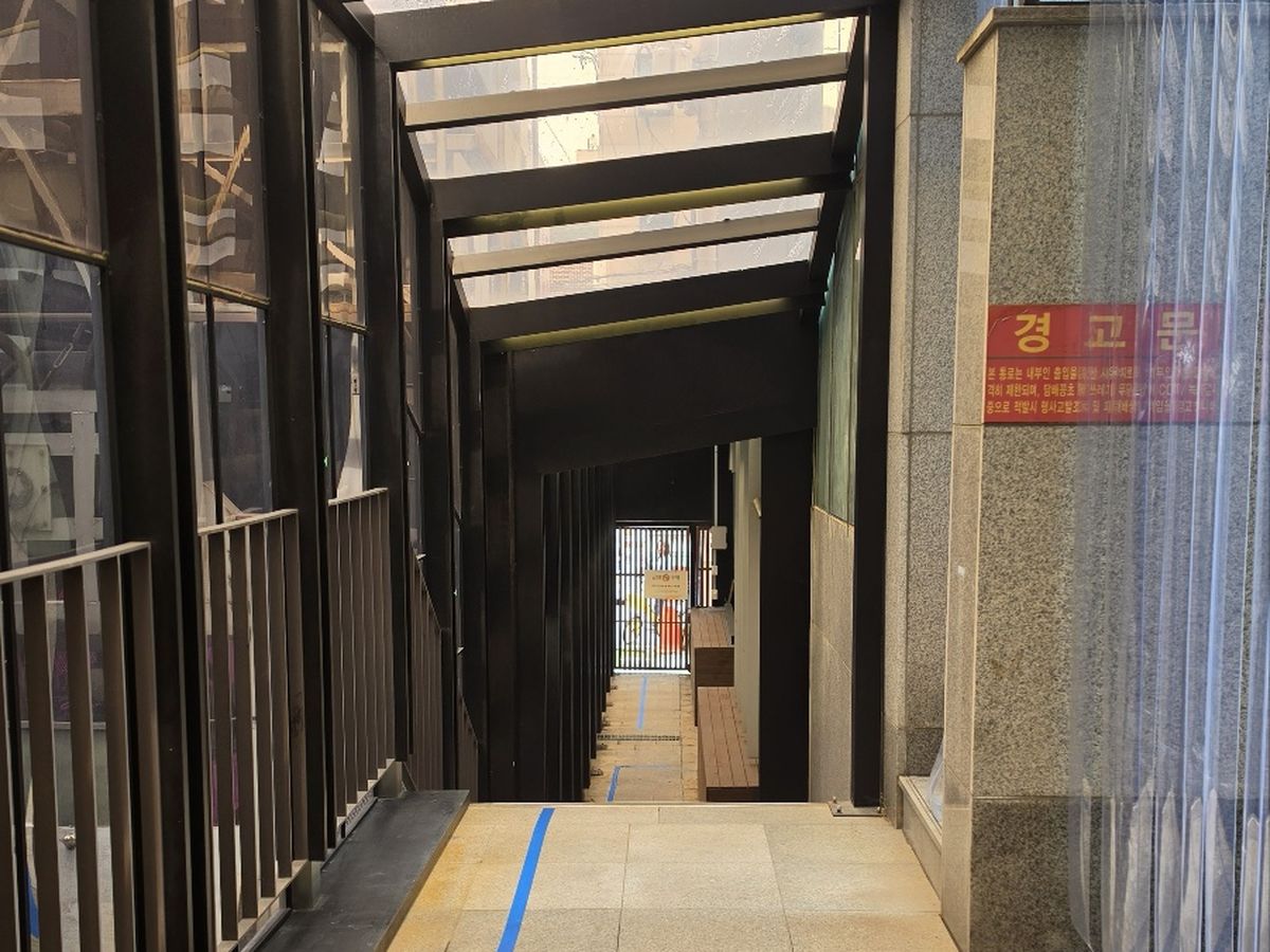 A동에서 B동으로 이어지는 지붕 덮인 연결통로 — 바닥에 파란 유도선이 있다